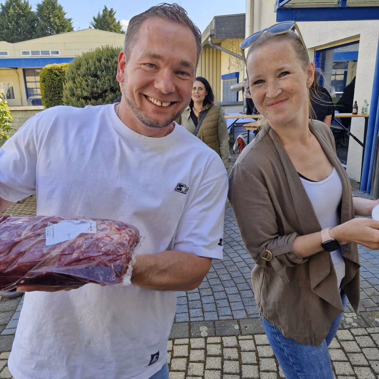 Labatzky - Pflege- & Betreuungsdienst - Mann und Frau sind im Freien und halten verschiedene Fleischstücke in der Hand